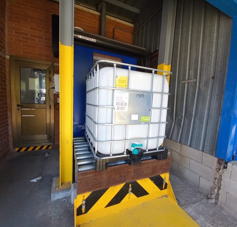 Conveyor-fed pallet IBC filler for agrochemical production plants